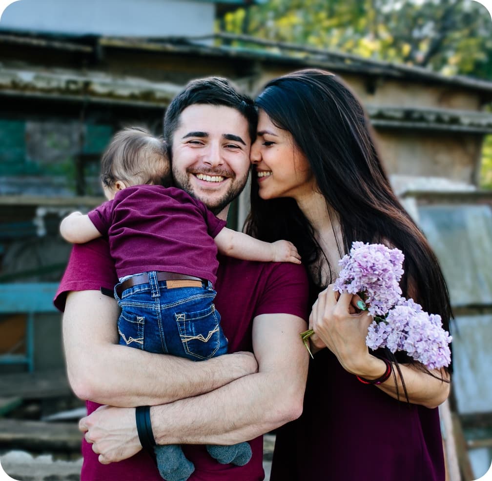 A family embracing, a father holding his child and a mother with flowers